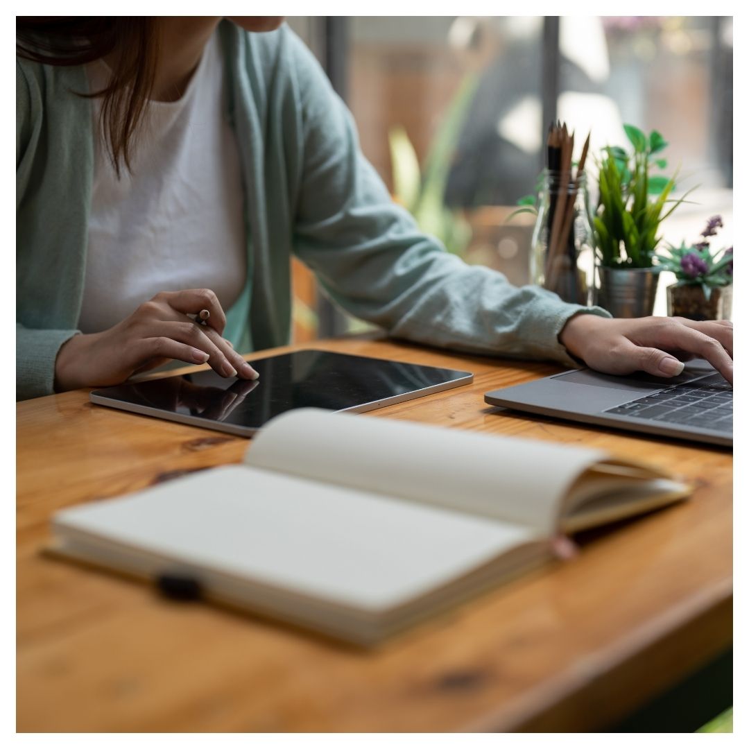 someone taking online class with book and tablet out on a desk